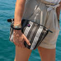 Person holding a striped pouch with water in the background