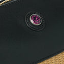 Detail of black vegan leather bag with logo button and beige straw body
