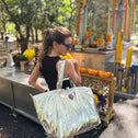 Woman carrying a medium gold metallic tote bag at a small temple in Thailand