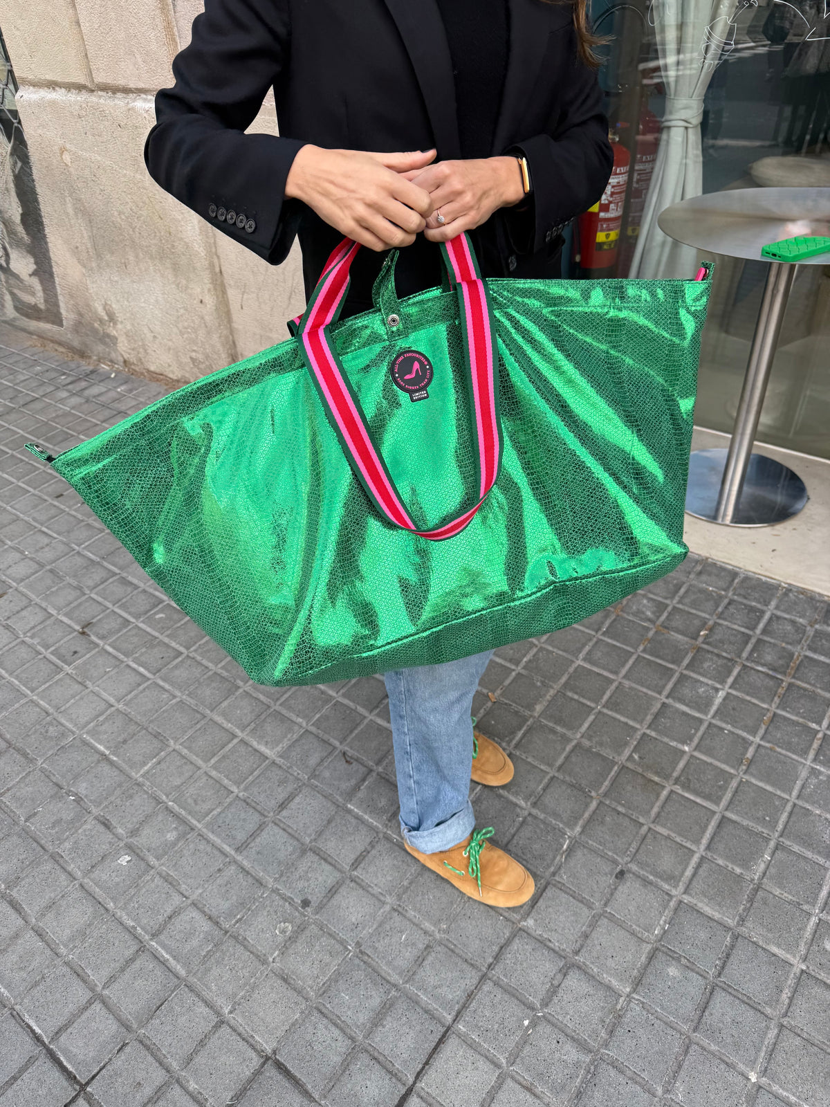 Metallic green VENEZIA large tote bag with red and white handles, carried on a city sidewalk.