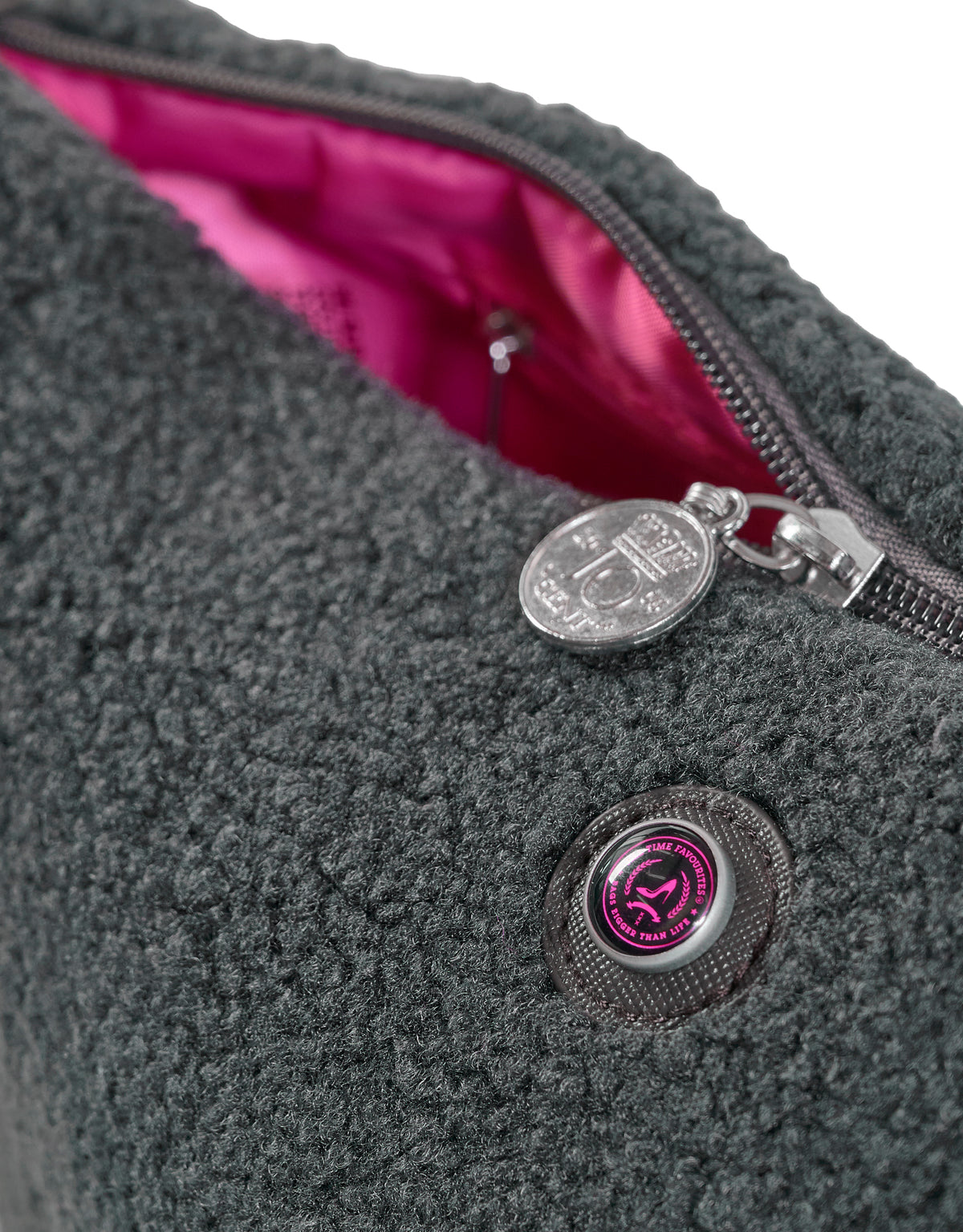 Grey teddy textured toiletry bag with silver zipper, pink lining, and round metal charm.